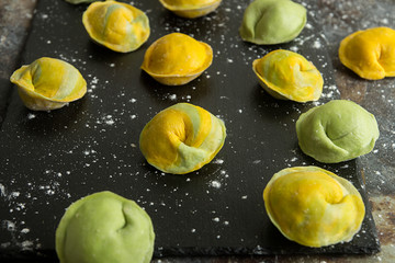 Homemade raw dumpling, yellow and green colors, traditional East European food before boiling. Top...