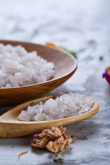 Composition of spa treatment on white background. Sea salt and flowers background, close up, top view, selective focus.