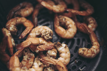Roasted shrimps with garlic and herbs. Seafood, shelfish. Shrimps Prawns grilled with spices and garlic on black stone background, copy space. Shrimps prawns on cast iron pan.