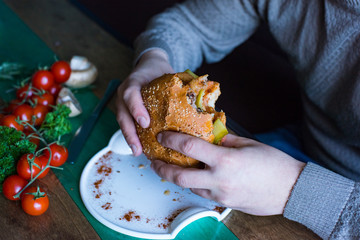A delicious hamburger for lunch in a cafe. People eat a hamburger