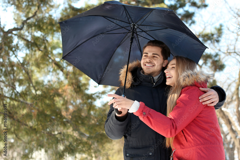 Wall mural Young romantic couple with umbrella in park