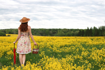 girl in a field of flowers with an umbrella and a hat