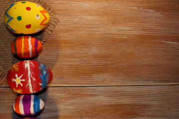 красивые разноцветные пасхальные яйца лежат на  деревянных досках       