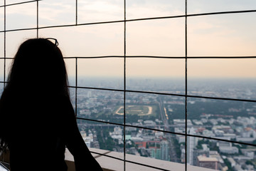 A girl's black .silhouette who looks down on the panorama of Bangkok. High cityscape from Baiyoke Sky Hotelю