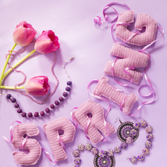 tulip floweres and spring word from knitted letters on pink paper