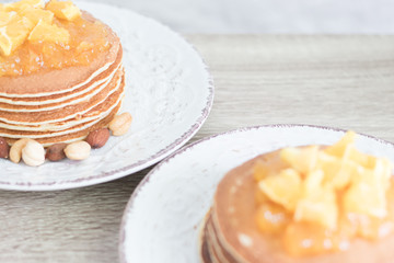 Two pancakes plates with orange jam and nuts on wooden table. Closeup. Copyspace