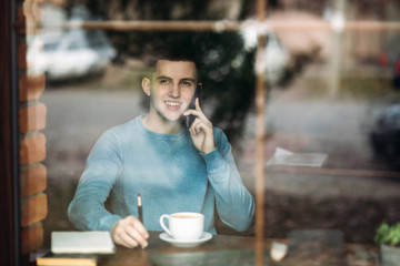 Man uses a laptop in a cafe while drinking coffee
