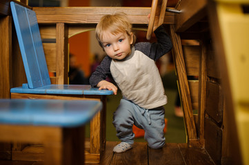 Cute little boy climbing into the toy wooden car