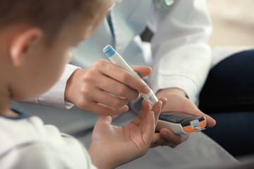 Doctor using lancet pen and digital glucometer to check diabetic boy's blood sugar level, closeup - obrazy, fototapety, plakaty