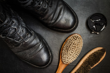 Men's military boots rme shoes, brush and shoe polish against a dark background flat lay top view
