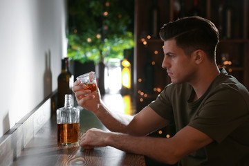Young man with glass of drink in bar. Alcoholism problem