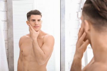 Obraz na płótnie Canvas Handsome man after shaving near mirror in bathroom