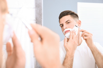 Handsome man shaving in bathroom