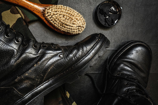 Men's military boots rme shoes, brush and shoe polish against a dark background flat lay top view