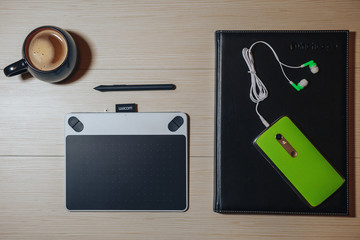 Flat lay photography of creative desk, Overhead view of graphic tablet, graphic pen, smartphone eyeglasses, keyboard and a cup of black coffee, Workspace desk of creative designer