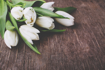 Bouquet of white tulips on a grey wooden table, copy space. Easter.