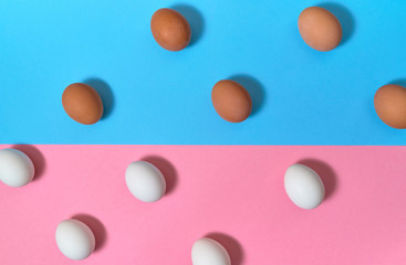 White and brown eggs on blue and pink pastel background, copy space. Boiled eggs on paper...