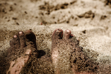 Sea foam, waves and naked feet on a sand beach.