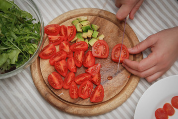 Cutting Red Tomato on Wooden Board. Process of Preparing Healthy Salad. Kitchen Background.