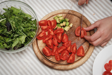 Cutting Red Tomato on Wooden Board. Process of Preparing Healthy Salad. Kitchen Background.