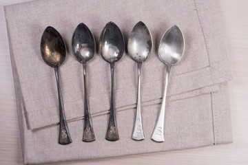 Stunning vintage old dirty silver spoons on silver napkin background