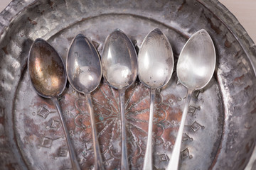 Stunning vintage old dirty silver spoons on silver metal background