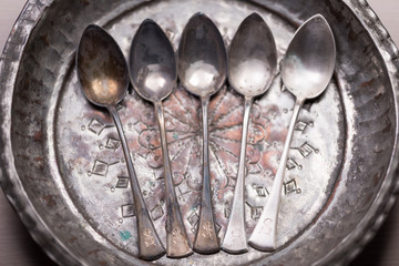 Stunning vintage old dirty silver spoons on silver metal background