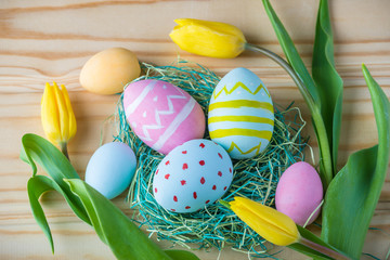 Colorful Easter eggs with yellow Tulip hand painted on a light wooden background. Festive spring card