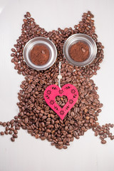 Valentine Heart and owl shape made from coffee beans on wooden surface.