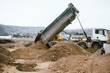 Industrial heavy duty dumper truck unloading gravel for leveling