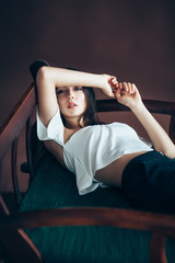 Fototapeta premium Beautiful thoughtful woman relaxing on sofa, hands bent behind head