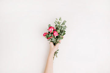 Woman hand hold rose flowers and eucalyptus bouquet on white background. Flat lay, top view spring...
