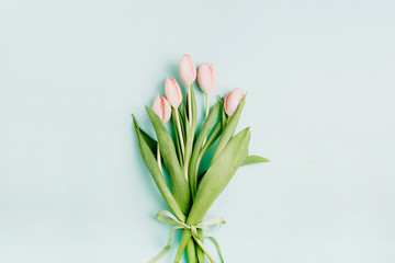 Pink tulip flowers bouquet on pale blue background. Flat lay, top view. Spring floral concept.