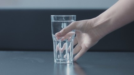 woman's hand picking a glass of water closeup with funny nail design