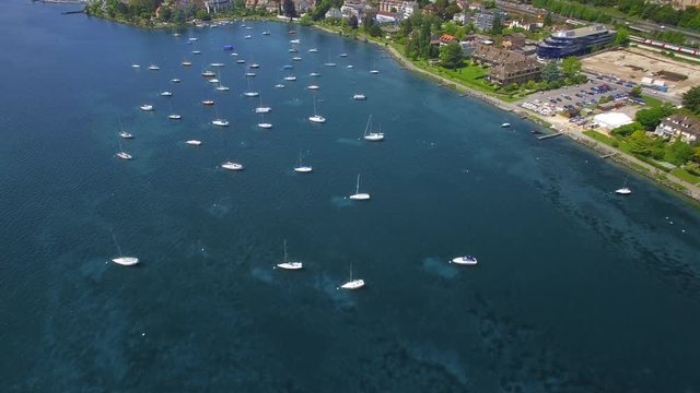 4K City by the lake cinematic drone shot. Camera tilting up to discover a lovely town with many boats
