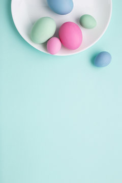 Conceptual Easter vertical background with white plate and painted eggs.