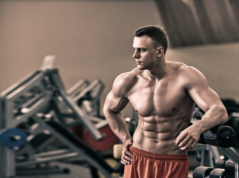 Young healthy man with perfect muscular body in the gym, the image was desaturated ang toned