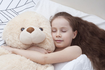 Beautiful 7-8 year Old Girl Sleeping Girl in the Bedwith Teddy Bear with Copy Space. Flat Lay.