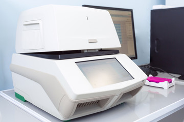 Female genetics worker placing the strips with DNA into the PCR thermal cycler or amplifier for PCR diagnostics