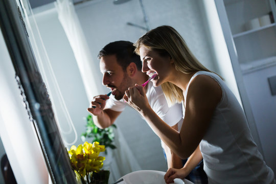 Happy Young Couple Brushing Teeth In Bathroom