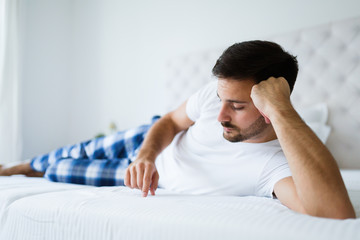 Portrait of unhappy man lying on bed