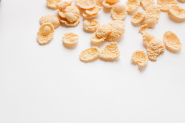 Delicious crispy cornflakes scattered on white background, healthy breakfast