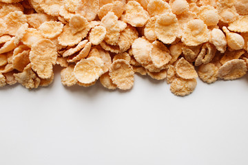 Delicious crispy cornflakes scattered on white background, healthy breakfast