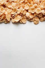 Delicious crispy cornflakes scattered on white background, healthy breakfast