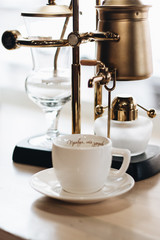 Cup of delicious coffee and retro style coffee machine, closeup