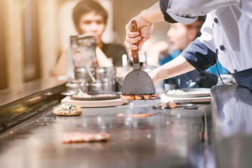 Hand of man take cooking of meat with vegetable grill, Chef cooking wagyu beef in Japanese teppanyaki restaurant