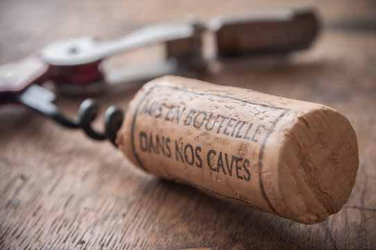 closeup of corks wine and pulls caps on wooden background with french text "mis en bouteille dans nos caves" traduction of bottled in our cellars