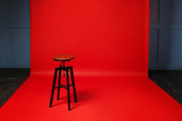 Wooden retro stool on red background. No one, free space on the right.