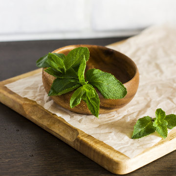 Leaves of fresh mint in a wooden bowl on the kitchen table