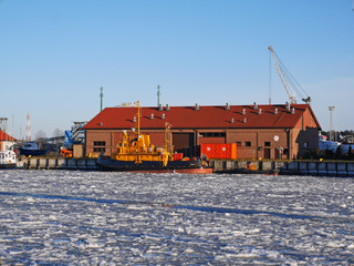 Water reservoir channel in winter and building with cranes